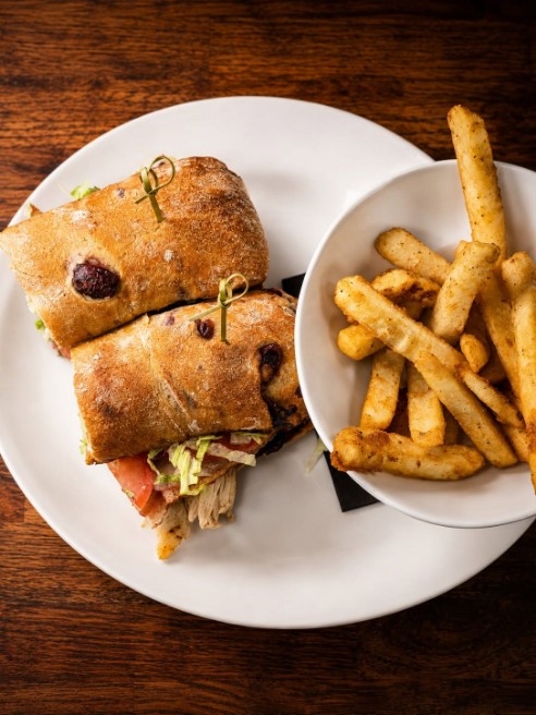 Sandwich halves with a bowl of fries