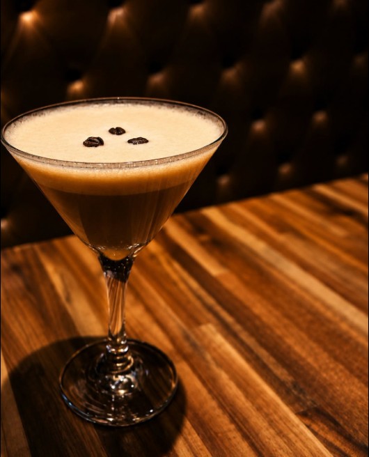 Coffee-coloured cocktail topped with foam and three coffee beans